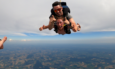 Deux personnes sautant en tandem en parachute au-dessus d'une campagne