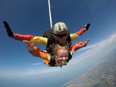 Deux personnes en parachute en tandem avec vue sur la côte.