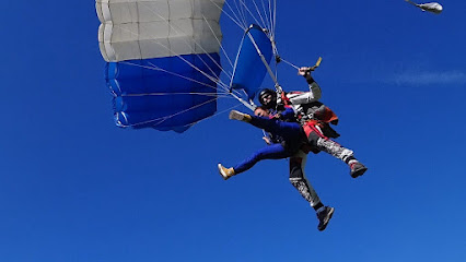 Deux personnes en tandem sautant en parachute sous un ciel bleu