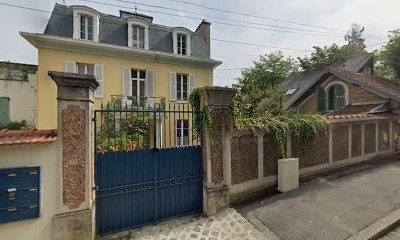 Maison jaune traditionnelle avec portail bleu, en journée.