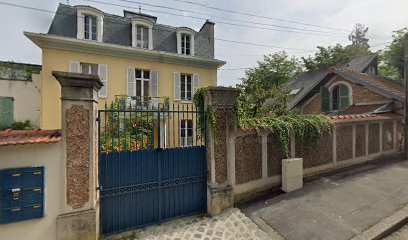 Maison jaune traditionnelle avec portail bleu, en journée.
