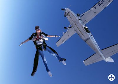Personne en parachute saute d'un avion en plein ciel bleu