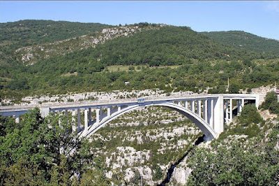 Pont en arc sur un canyon entouré de collines verdoyantes