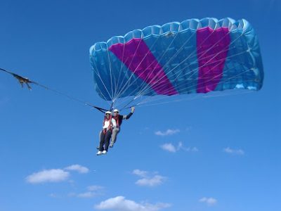 Deux personnes font du parapente sous un ciel bleu