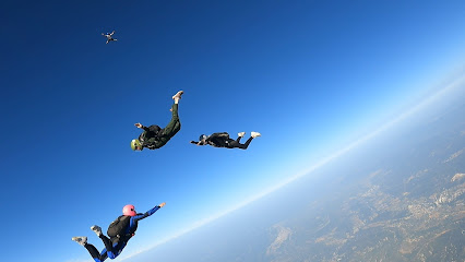 Trois parachutistes en chute libre sous un ciel bleu clair