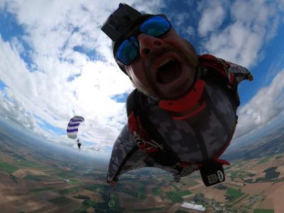 Deux parachutistes en chute libre au-dessus d'une campagne.