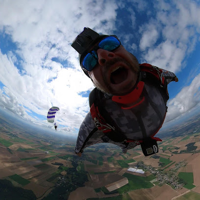 Deux parachutistes en chute libre au-dessus d'une campagne.
