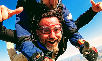 Homme souriant faisant un saut en parachute tandem