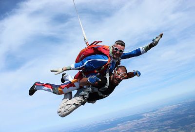 Deux personnes en parachute tandem en plein ciel bleu