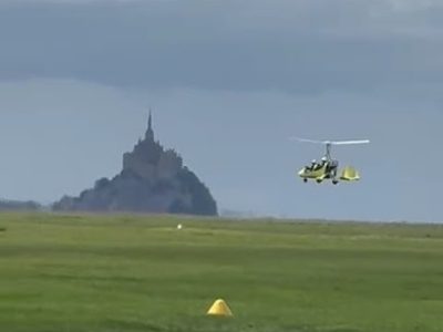 Gyrocoptère volant près du Mont-Saint-Michel sous un ciel nuageux