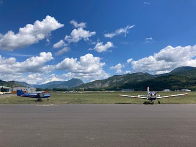 Deux petits avions sur une piste, montagnes en arrière-plan.