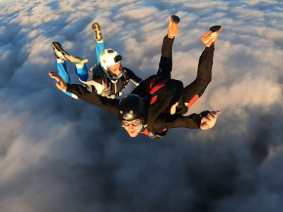 Trois parachutistes en chute libre au-dessus des nuages