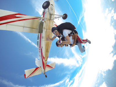Deux personnes en parachutisme tandem sous un avion.
