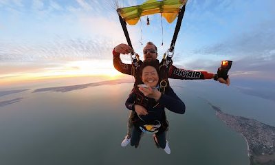 Deux personnes en parachute au-dessus d'un paysage côtier au crépuscule