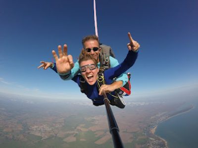 Deux personnes effectuant un saut en parachute en tandem au-dessus de la campagne