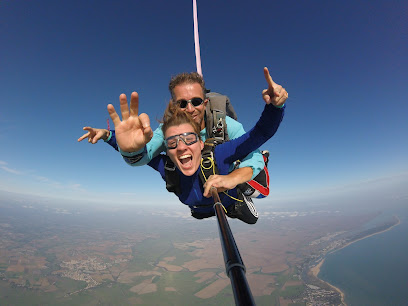 Deux personnes effectuant un saut en parachute en tandem au-dessus de la campagne