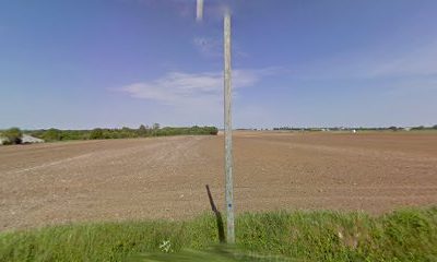 Champ labouré sous un ciel bleu avec un poteau en bois au centre
