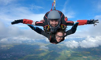 Deux personnes en saut en parachute en tandem dans le ciel.