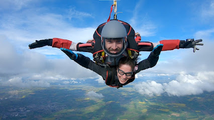 Deux personnes en saut en parachute en tandem dans le ciel.