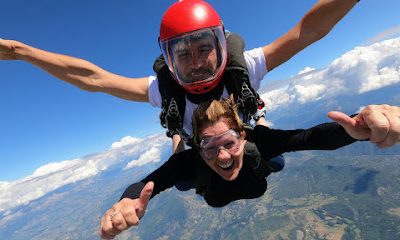 Deux personnes font du parachutisme avec vue sur les montagnes en arrière-plan.