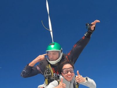 Deux personnes en tandem sautant en parachute dans un ciel bleu