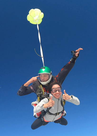Deux personnes en tandem sautant en parachute dans un ciel bleu