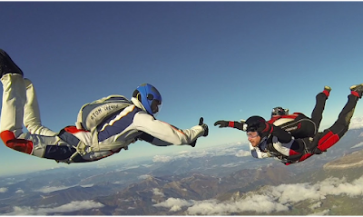 Deux parachutistes en pleine chute libre au-dessus des montagnes
