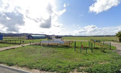 Aérodrome entouré de verdure sous un ciel bleu avec nuages