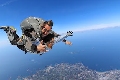Deux personnes en parachute tandem au-dessus d'un paysage côtier.