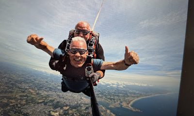 Deux personnes sautant en parachute au-dessus d'un paysage côtier.