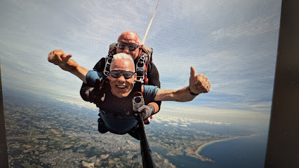 Deux personnes sautant en parachute au-dessus d'un paysage côtier.