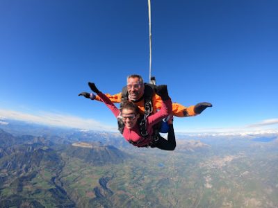 Deux personnes en parachute tandem au-dessus des montagnes.