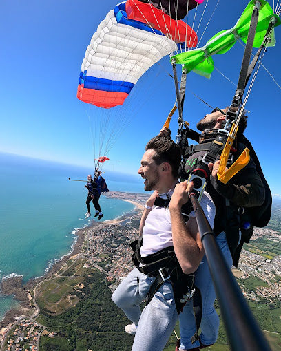 Deux personnes en tandem parachutisme au-dessus d'une côte ensoleillée.